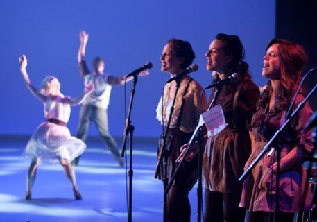Performers singing and dancing on stage.