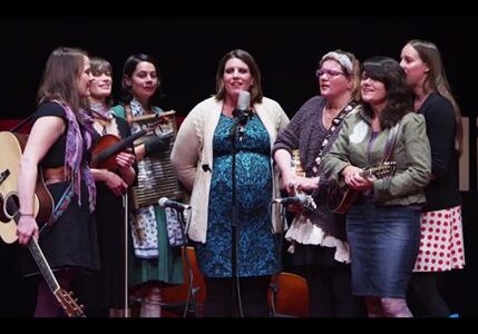 Group of women performing with musical instruments.