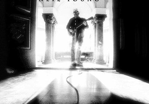 Man playing guitar in dramatic lighting.