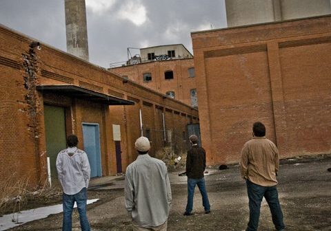 Four people standing near an industrial building.