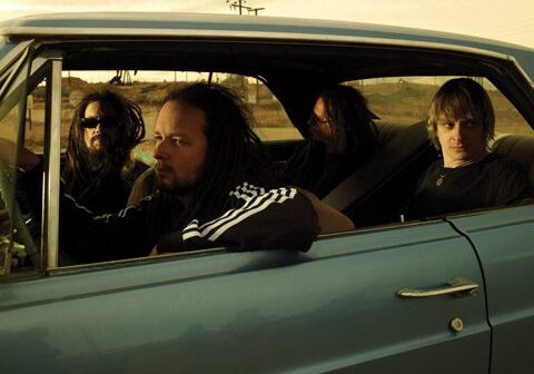 Four men sitting in a blue car.