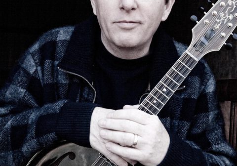 Man holding a mandolin, wearing glasses.