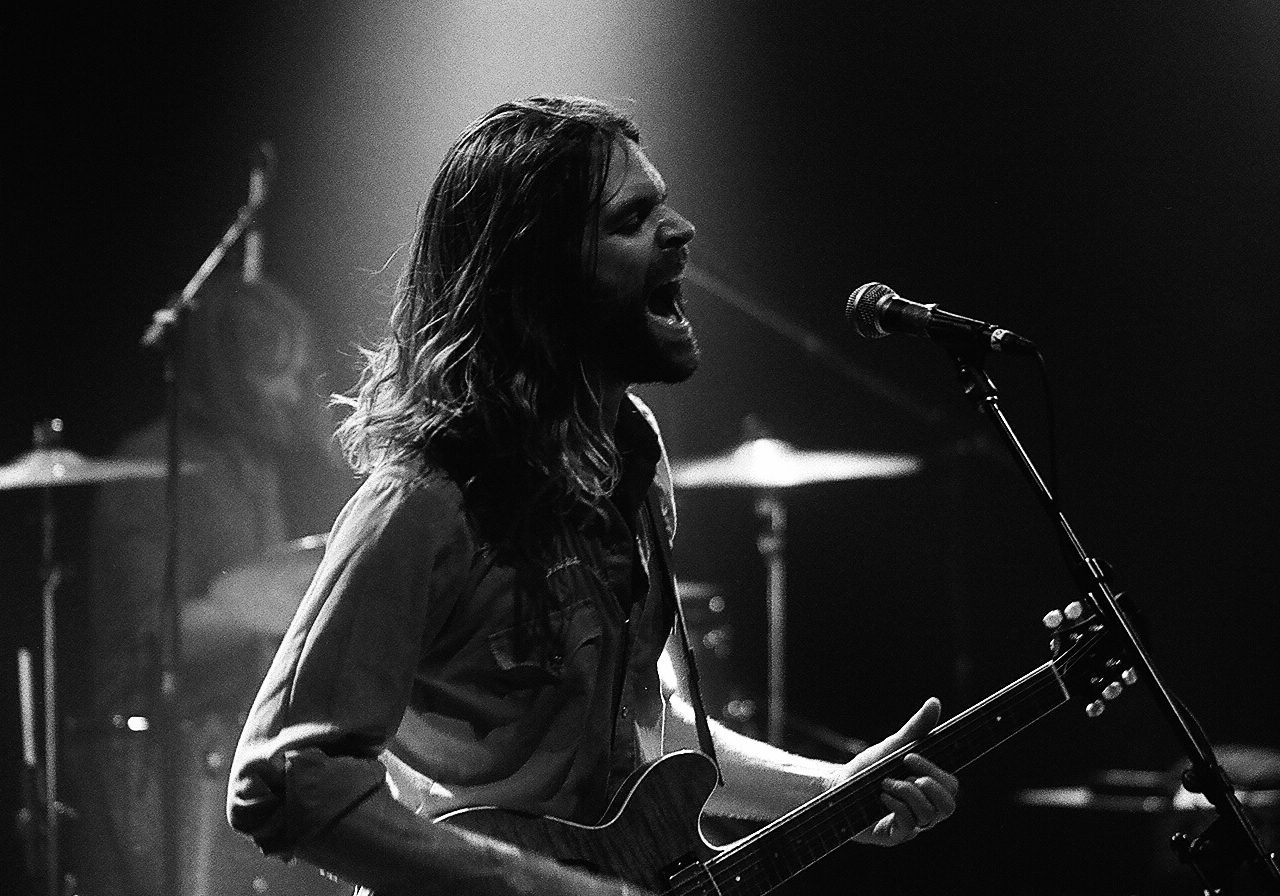 Musician passionately performing on stage with guitar.