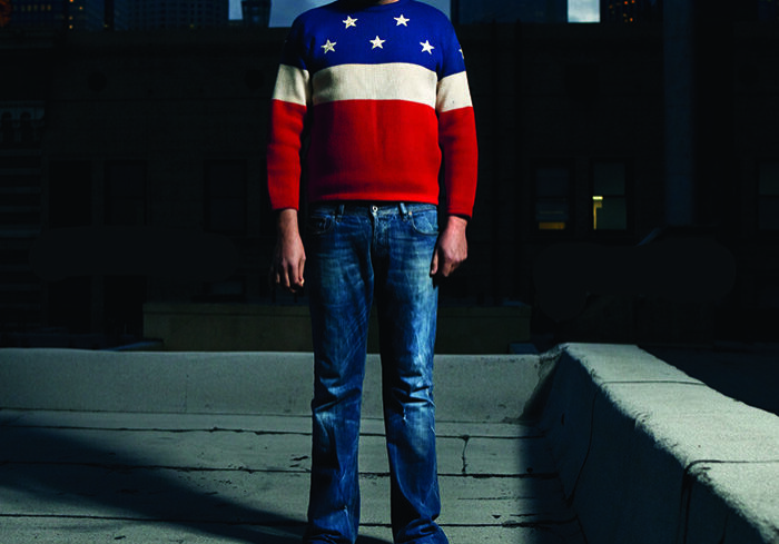 Man in star sweater on rooftop at night.