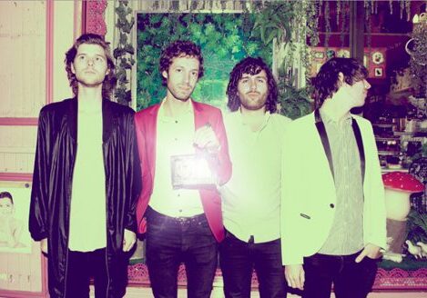 Four men standing in vintage-themed room.