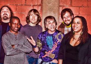 Group of people smiling against brick wall.