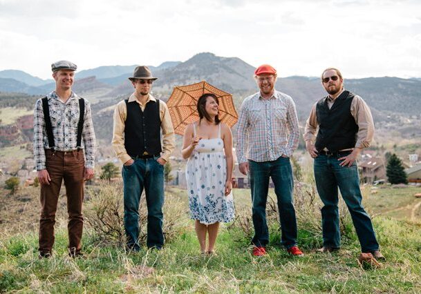 Group posing outdoors with mountains in background.