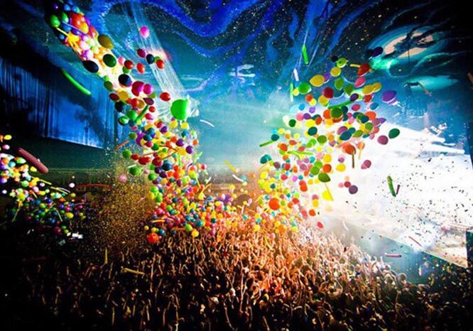 Concert crowd with colorful balloons and confetti.