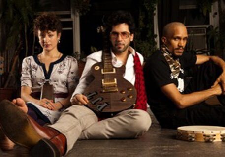 Three people sitting with guitar and tambourine.