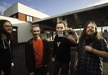 Four people smiling outside a building.