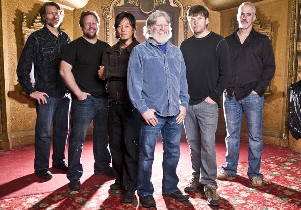 Group of six men in ornate room.