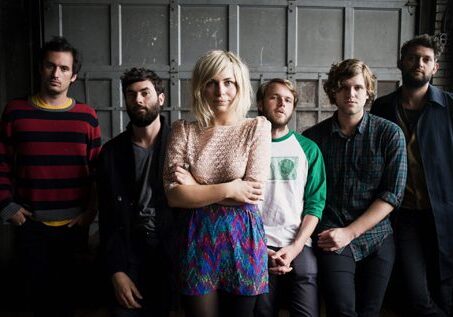 Group of six people standing together indoors.
