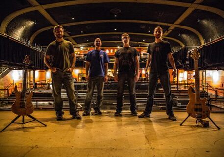 Band posing on stage with instruments.