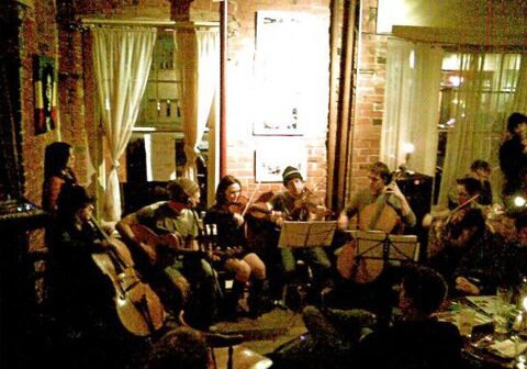 Musicians performing in a cozy, dimly-lit room.