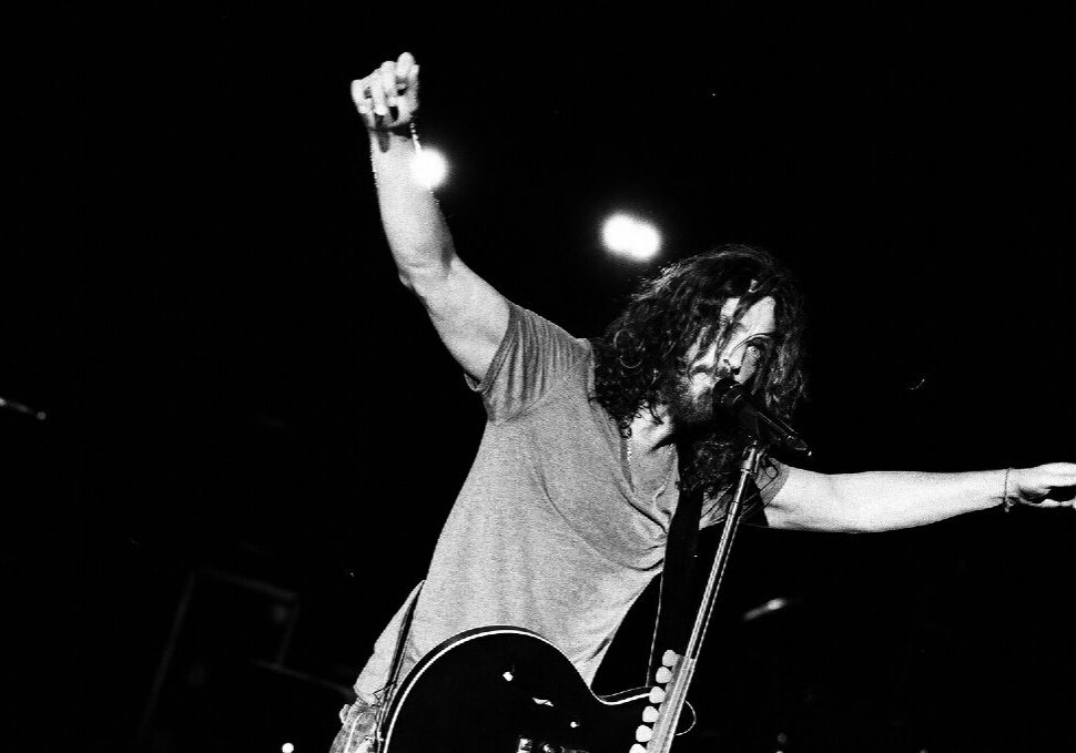 Musician performing energetically with guitar on stage.