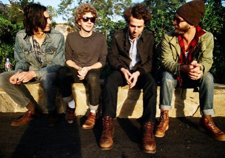 Four men sitting on a stone wall.