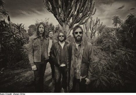 Four men standing in a desert landscape.