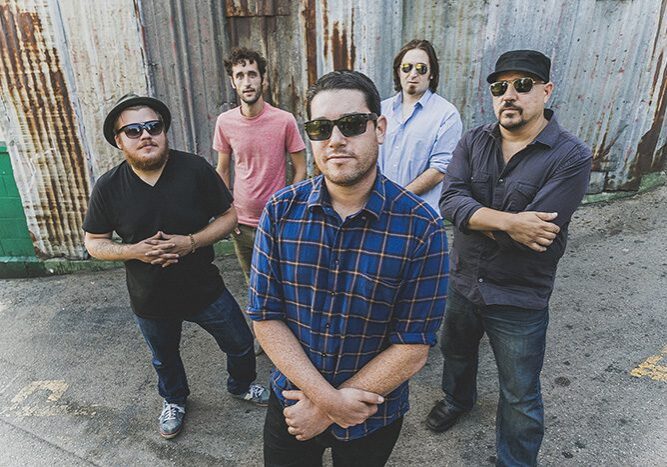 Five men posing in casual outdoor setting.