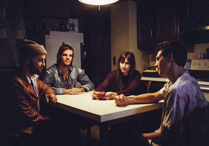 Four people sitting at a kitchen table.