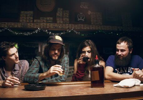 Four people sitting at a bar counter.
