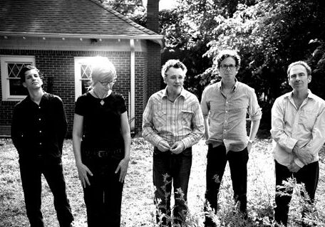 Five people standing outside near a building.