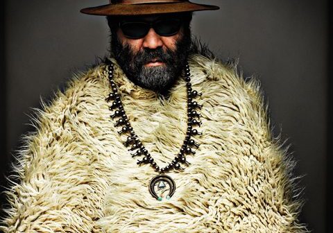 Man in fur coat, hat, and sunglasses.