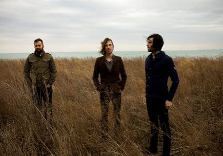 Three people standing in a grassy field.