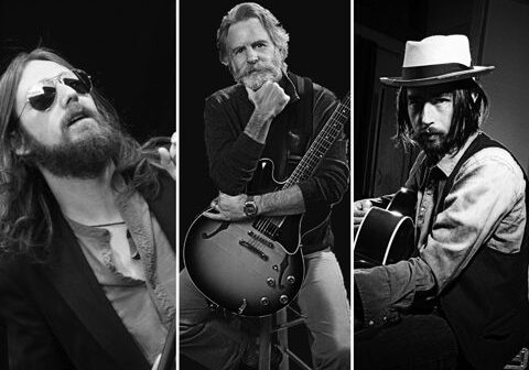 Three musicians with guitars in black and white.