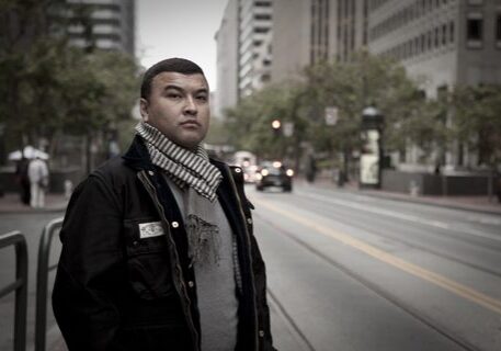 Man standing on city street in scarf.