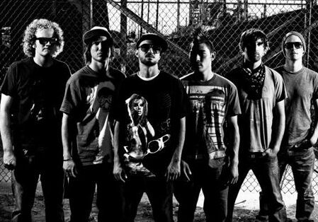 Band members posing in front of fence.