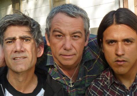 Three men standing closely, looking serious.