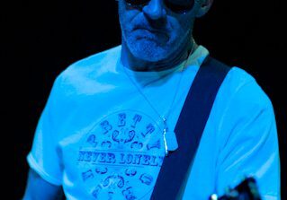 Bald man playing guitar on stage.