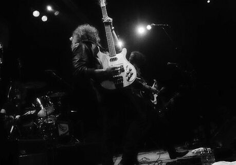 Rock band performing on stage with instruments.