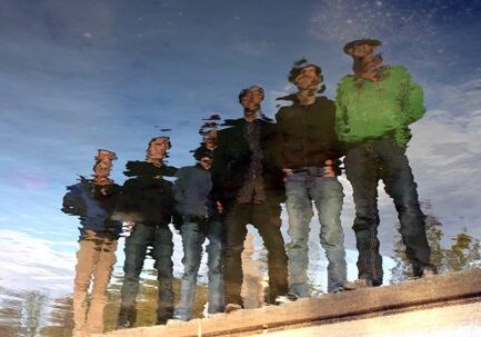 Reflection of people standing by the water.