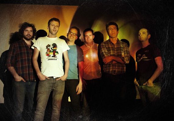 Group of six men posing together indoors.