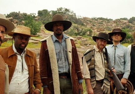 Group of cowboys standing in outdoor setting.