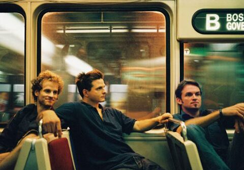 Three men sitting on a subway train.