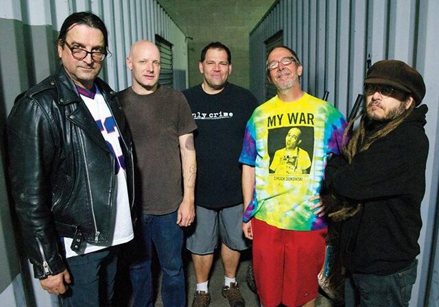 Five men standing in a row, smiling.