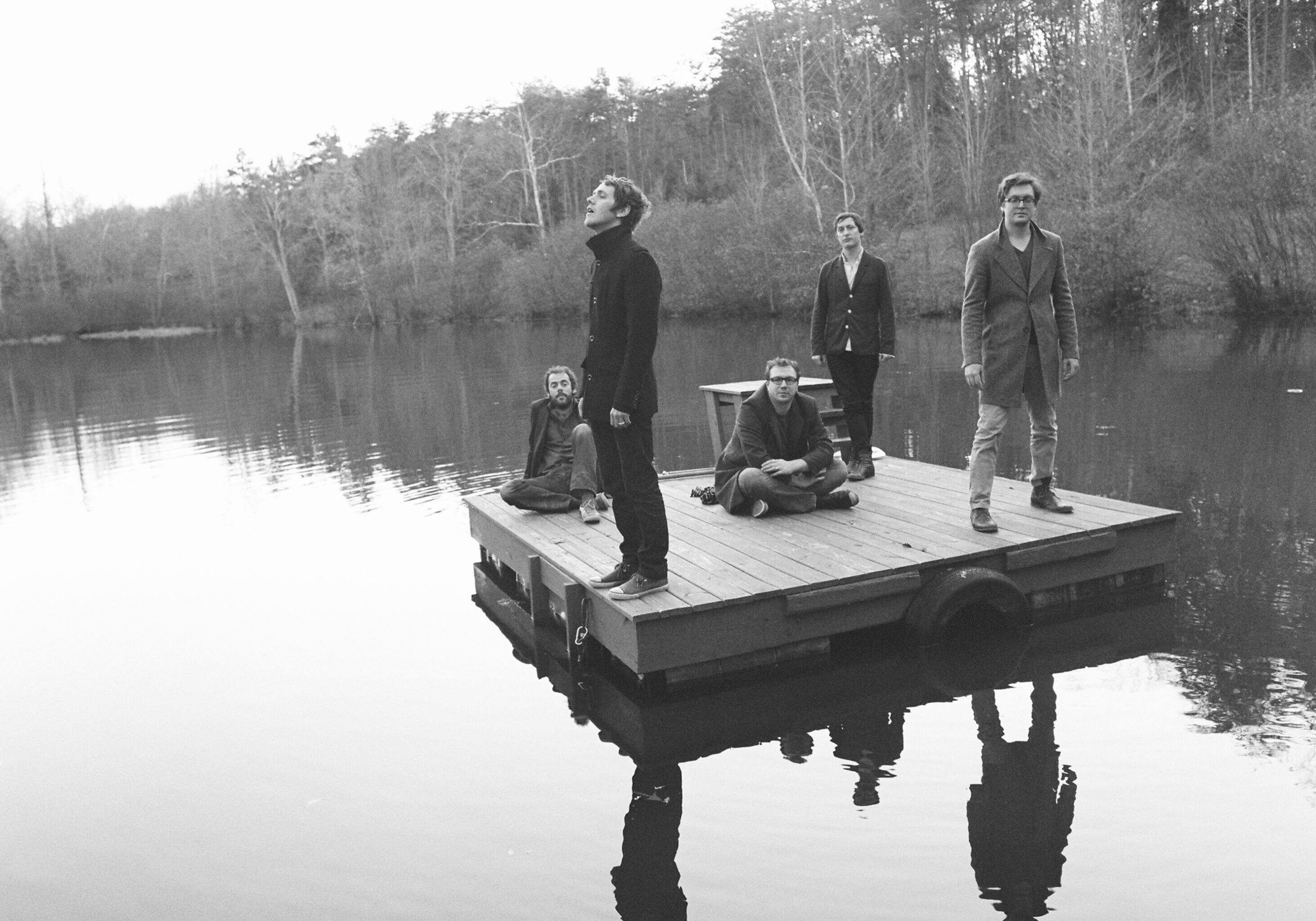 People on a wooden raft in lake.