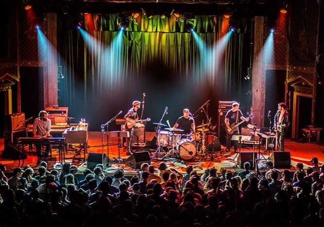 Band performing live on stage with audience.