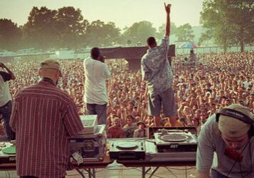 Concert crowd with DJs and performers on stage.