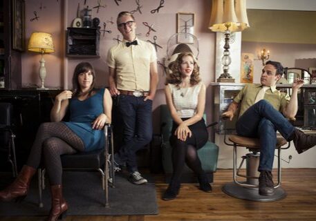 Four people sitting in a retro salon.