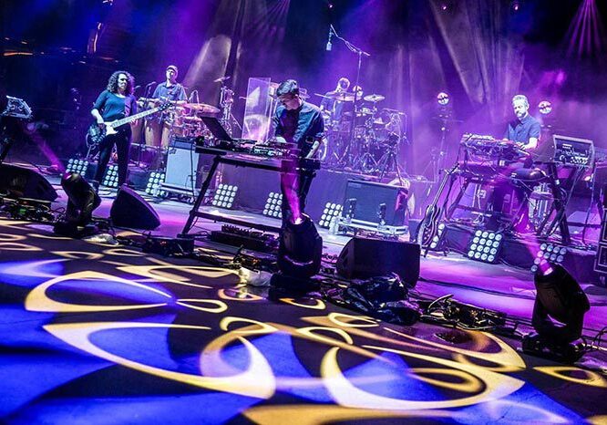Live band performing on colorful illuminated stage.