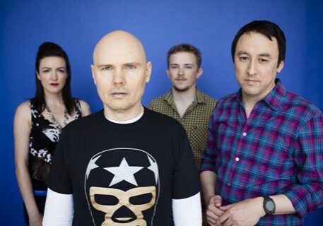 Four people posing against a blue background.