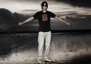 Person standing on beach at dusk.