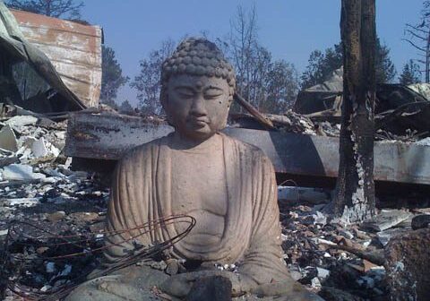 Buddha statue amidst rubble and debris.