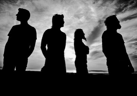 Silhouettes of four people against cloudy sky.