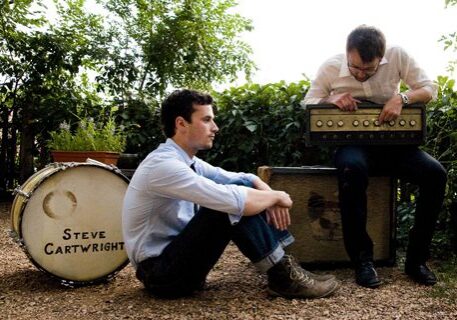 Two men with musical equipment outdoors.