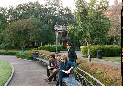 Four people sitting on park benches outdoors.