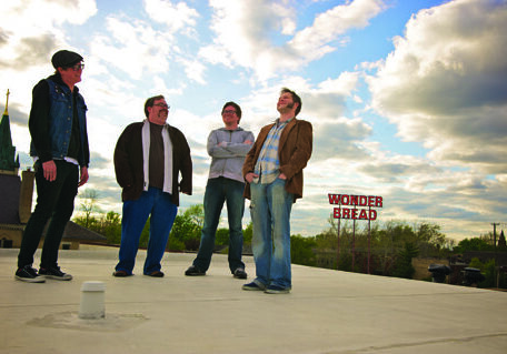 Four people standing on a rooftop smiling.